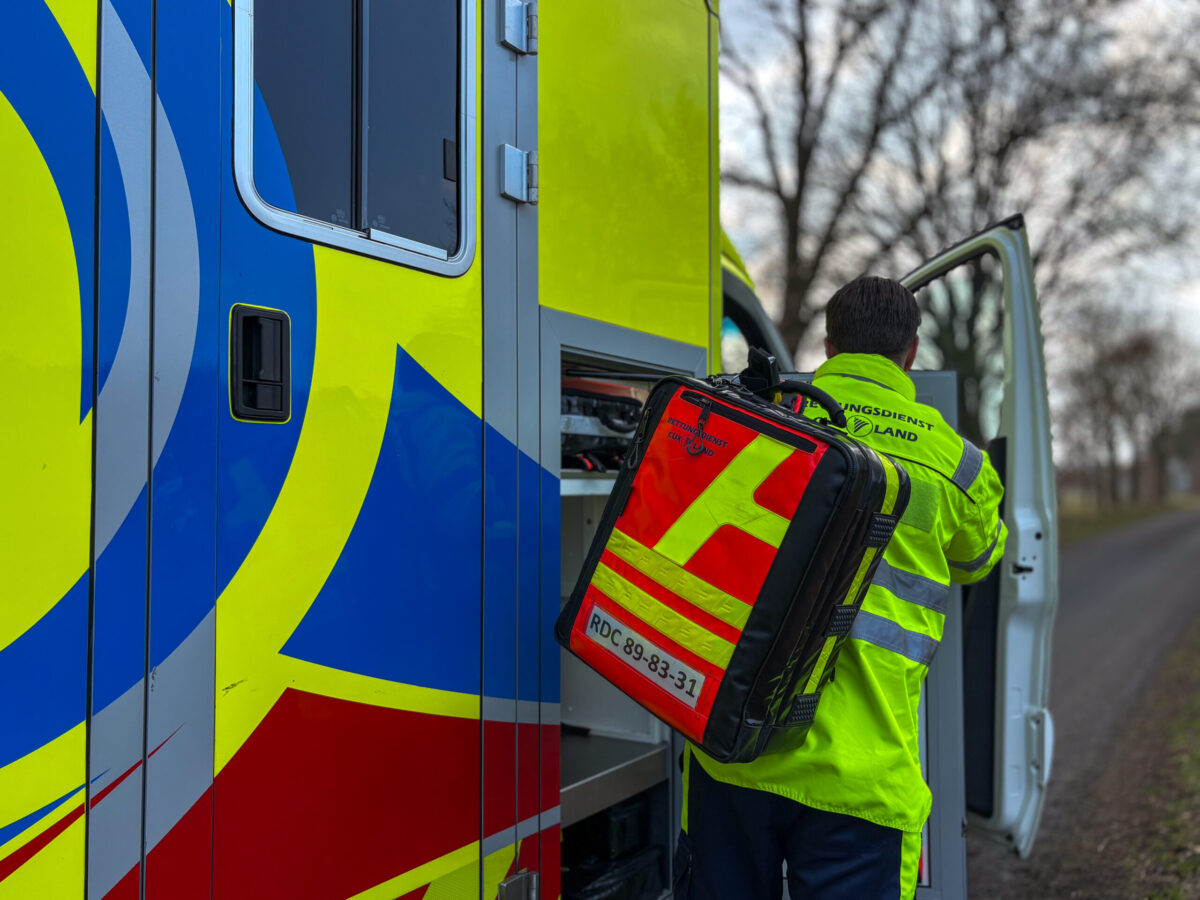Ein Mitarbeiter des Rettungsdienstes hebt einen Notfallrucksack aus dem Rettungswagen